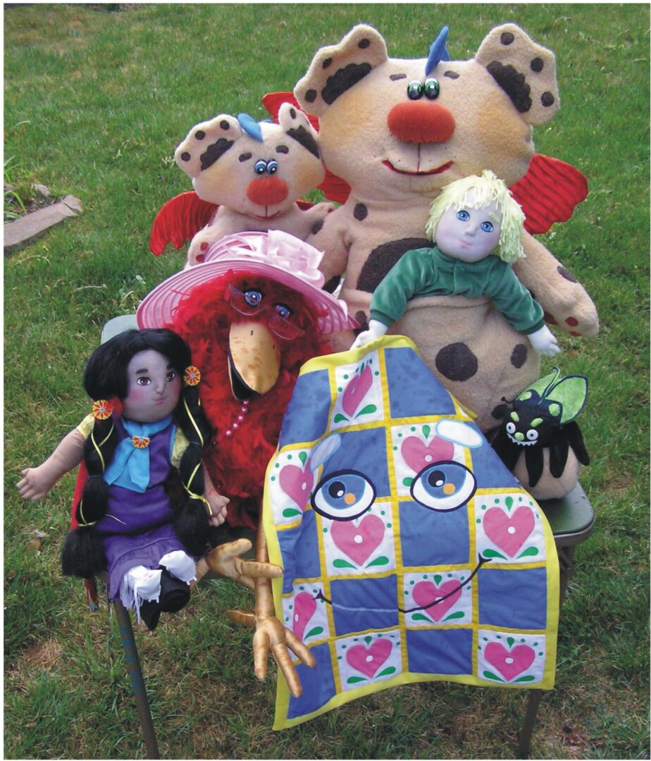 A group of colorful handcrafted dolls arranged on grass.