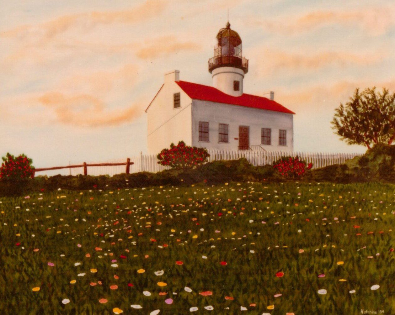 A quaint white church with a red roof on a grassy hill at sunset.