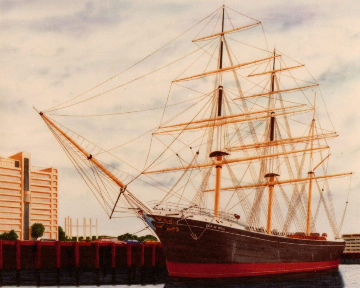 Historic tall ship docked near an urban waterfront at sunset.