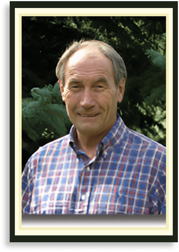 Smiling elderly man in a plaid shirt outdoors.