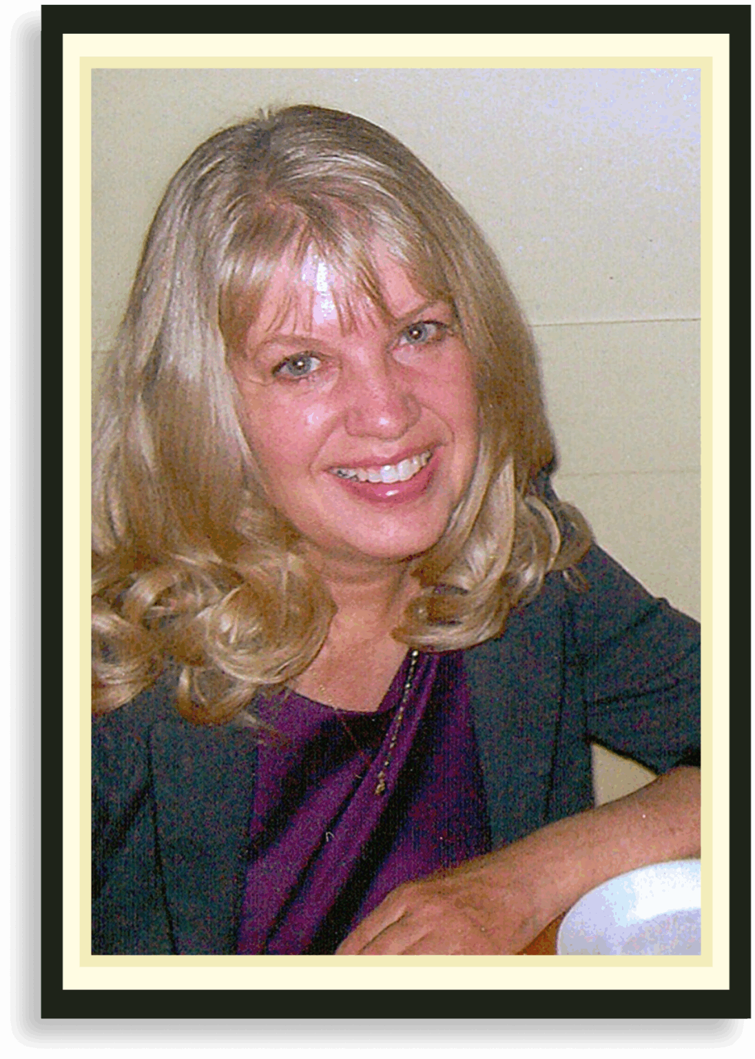 Smiling woman with blonde hair poses indoors.